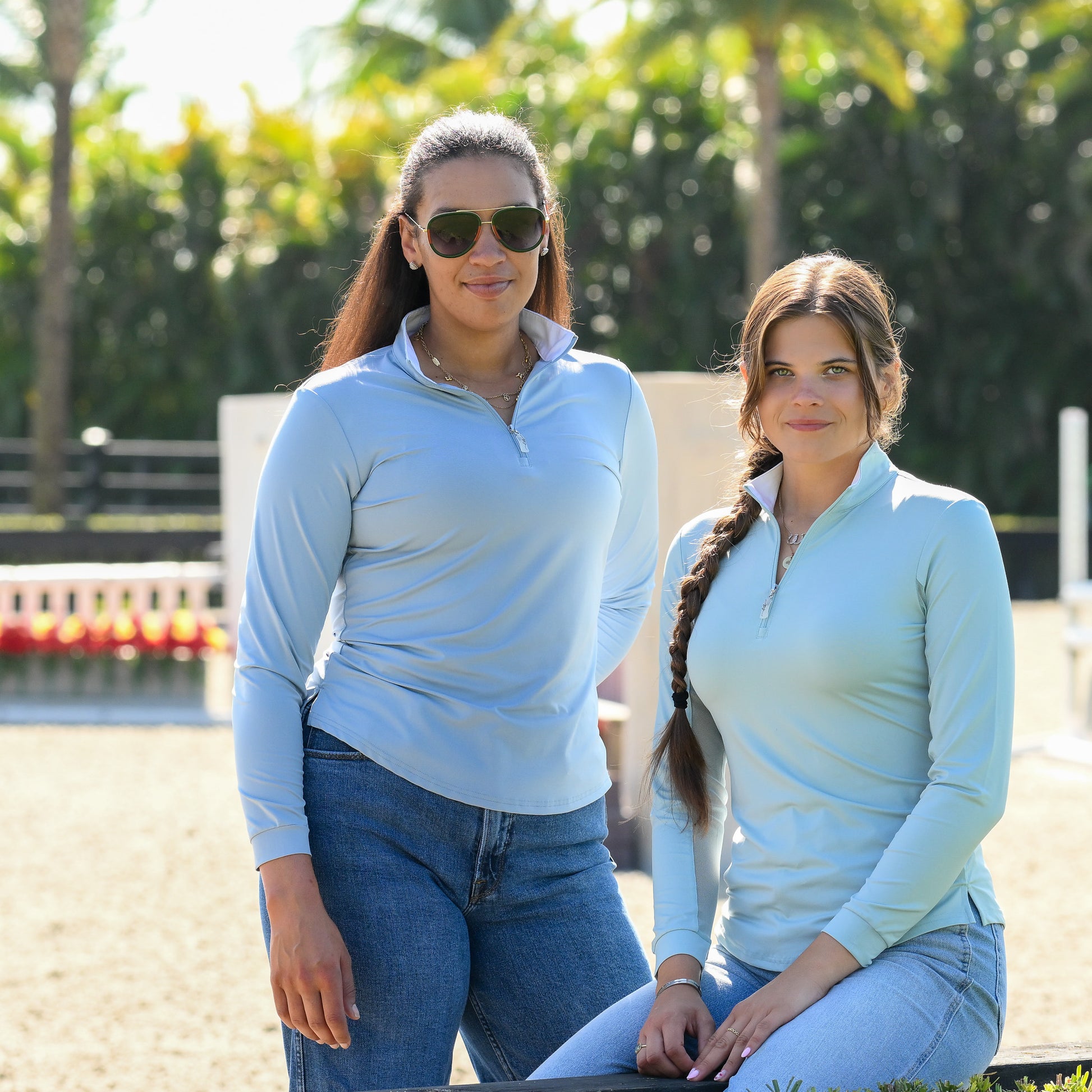 Two young women wearing EA Limited Inc.'s Contrast Collar Sun Shirt in Ether Green/White and Fog Blue/White, featuring quarter zip and UPF 50+ protection, happily posing together