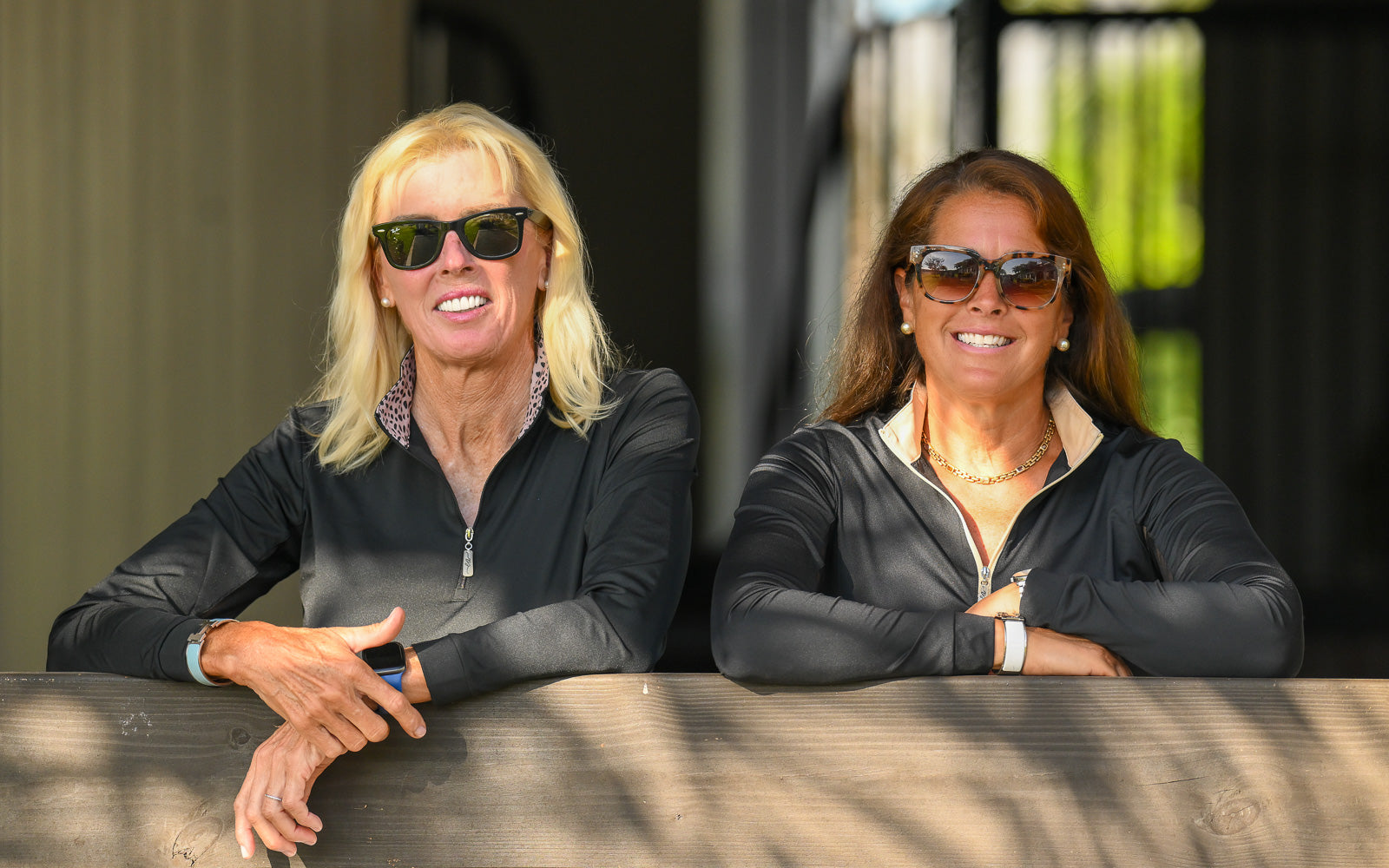 Two female equestrians striking a pose in their EA Limited Inc.'s UPF 50+ sun shirts, designed to protect against harmful sun rays.