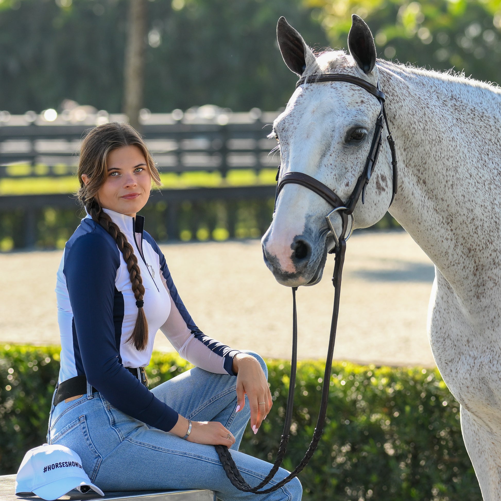 Young female equestrian in a stylish EA Limited Inc. Contrast Panel Sun Shirt in the color Navy/White, featuring a quarter zip design, posing confidently alongside her horse, both enjoying the UPF 50+ sun protection.
