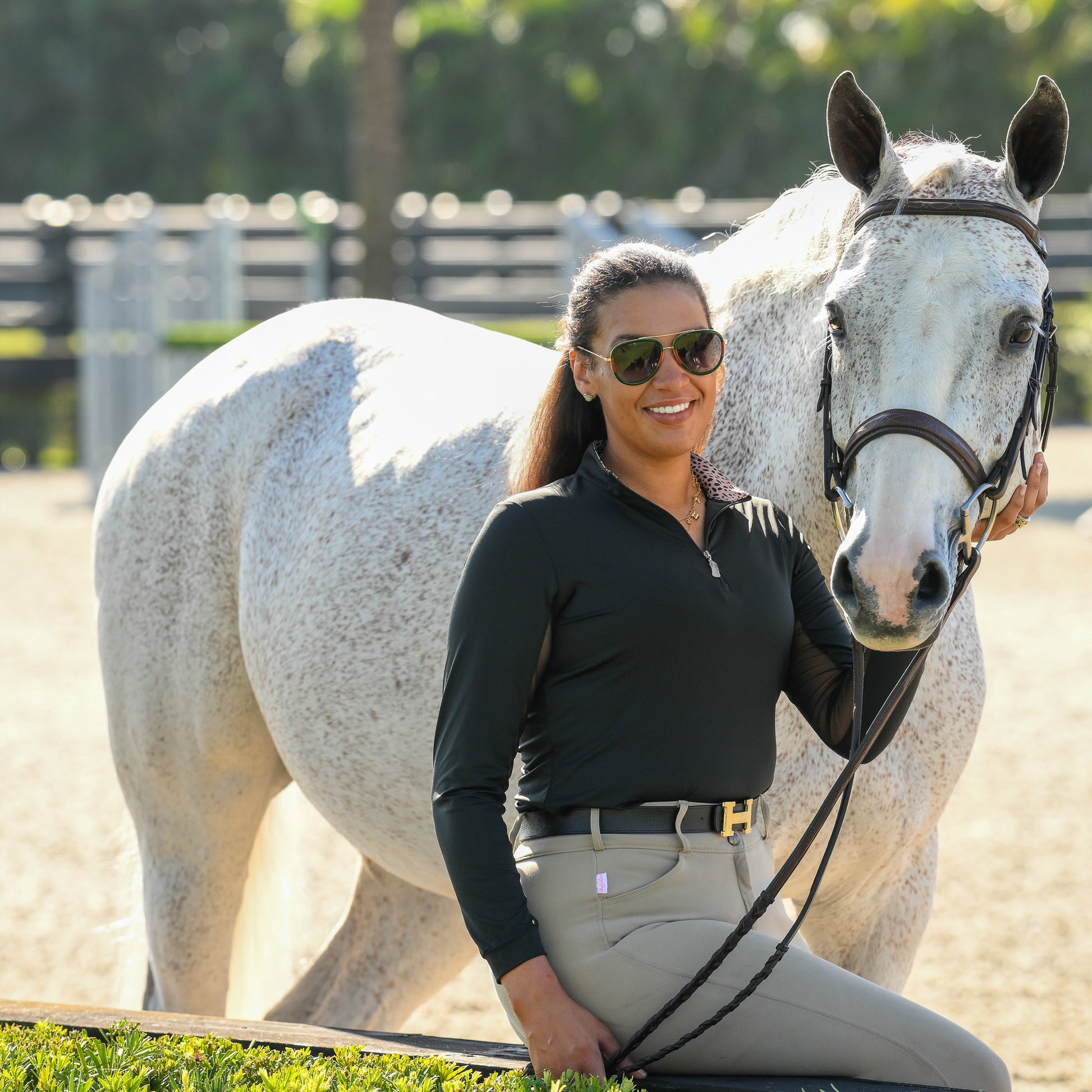 Young female equestrian wearing the Wild Thing Sun Shirt by EA Limited Inc., featuring a quarter-zip design, UPF 50+ protection, and a leopard print inside collar, confidently poses beside her horse.